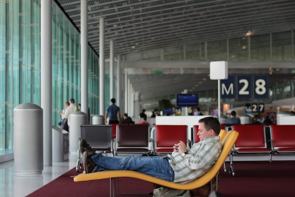 Solo traveller sitting in airport waiting area near departure gate for flight refund guide