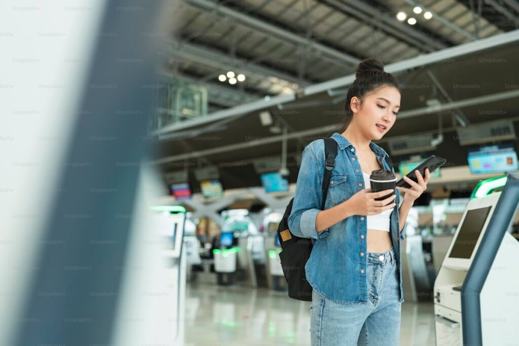 Young woman using smartphone at airport self-service kiosk for Digi Yatra paperless entry