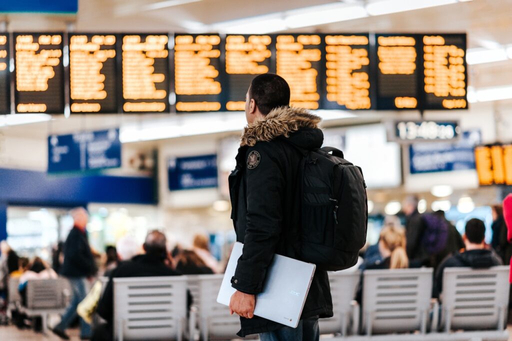 Traveller checking flight schedule on LED departure board inside airport terminal for web check-in